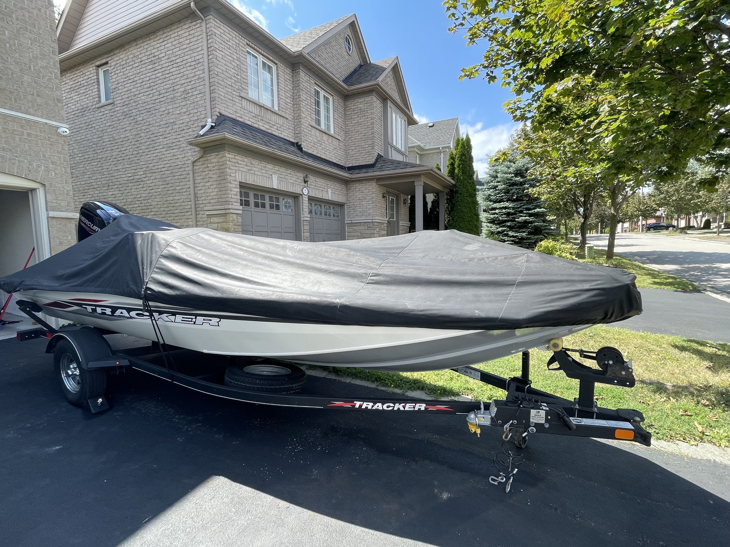 Boat with cover on trailer, front 3/4 view showing trailer hitch